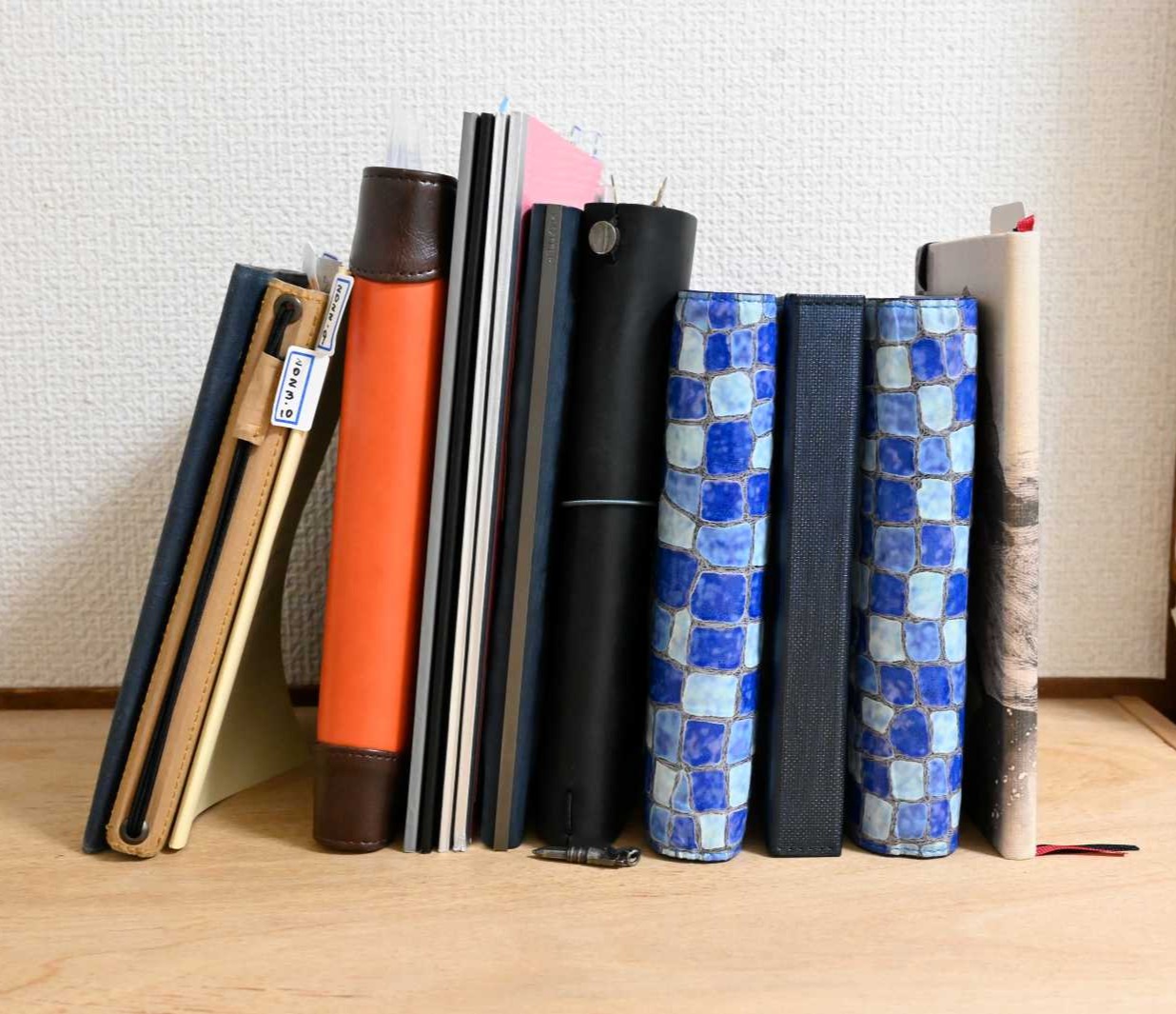 上達の研究家ワタタクが使ってきたシステム手帳や綴じ手帳。立てて並べている。