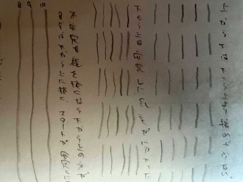 WSN: A-008 縦線練習ノートの右ページクローズアップ。下から上へ引いた際の不安定な線の震えと、「下から上は描きにくい。描きなれてない」という考察の手書き文字が詳細に確認できる。